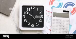 calculadora documentos e relogio sobre mesa