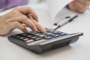 maos segurando calculadora sobre documentos financeiros