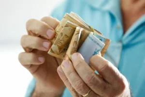 maos segurando carteira e dinheiro com inss