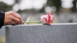 maos segurando documento e flores no tumulo