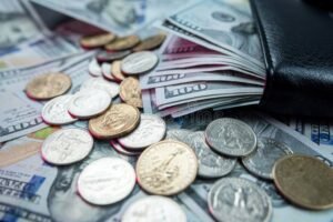 moeda e carteira com notas espalhadas