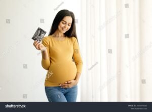 mulher gravida segurando ultrassom sorridente