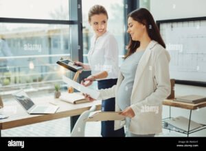 mulher gravida sorrindo com documentos trabalhistas