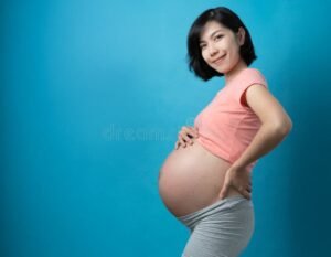 mulher gravida sorrindo segurando barriga