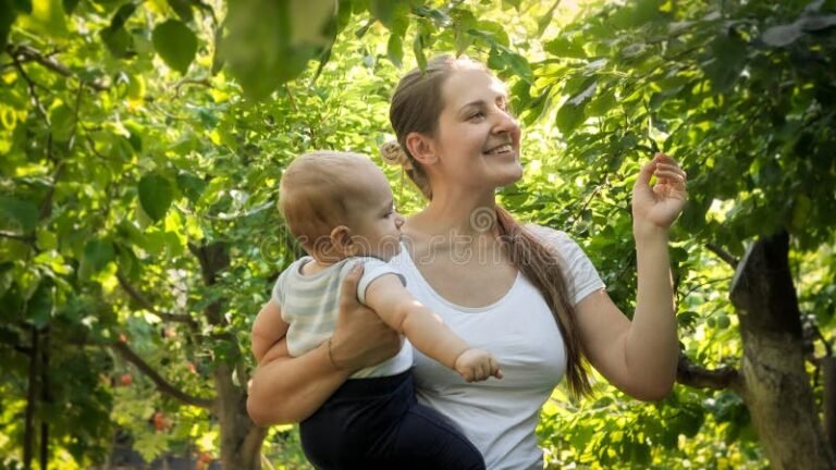 mulher sorrindo com bebe em jardins ensolarados