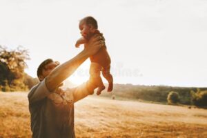 pai feliz segurando bebe ao ar livre