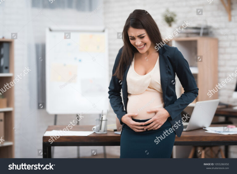 trabalhadora gravida segurando barriga no escritorio